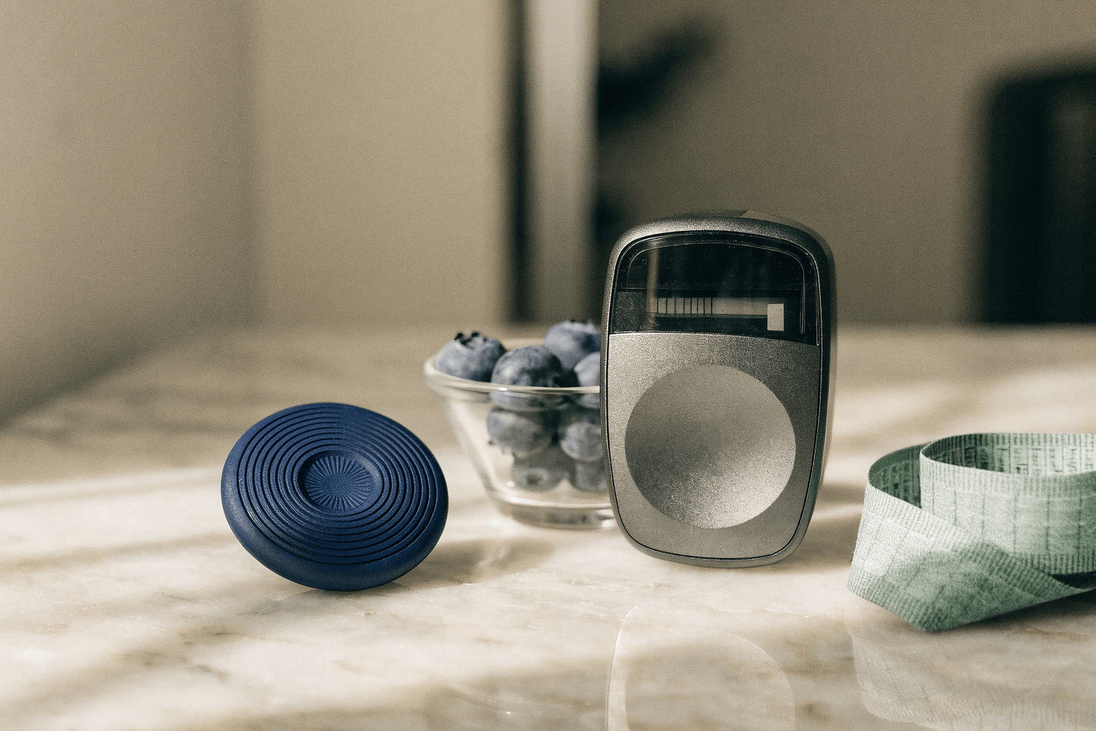 Sensor de monitoramento contínuo de glicose, um glicosímetro e uma tigela de mirtilos sobre mesa · manejo do diabetes tipo 2