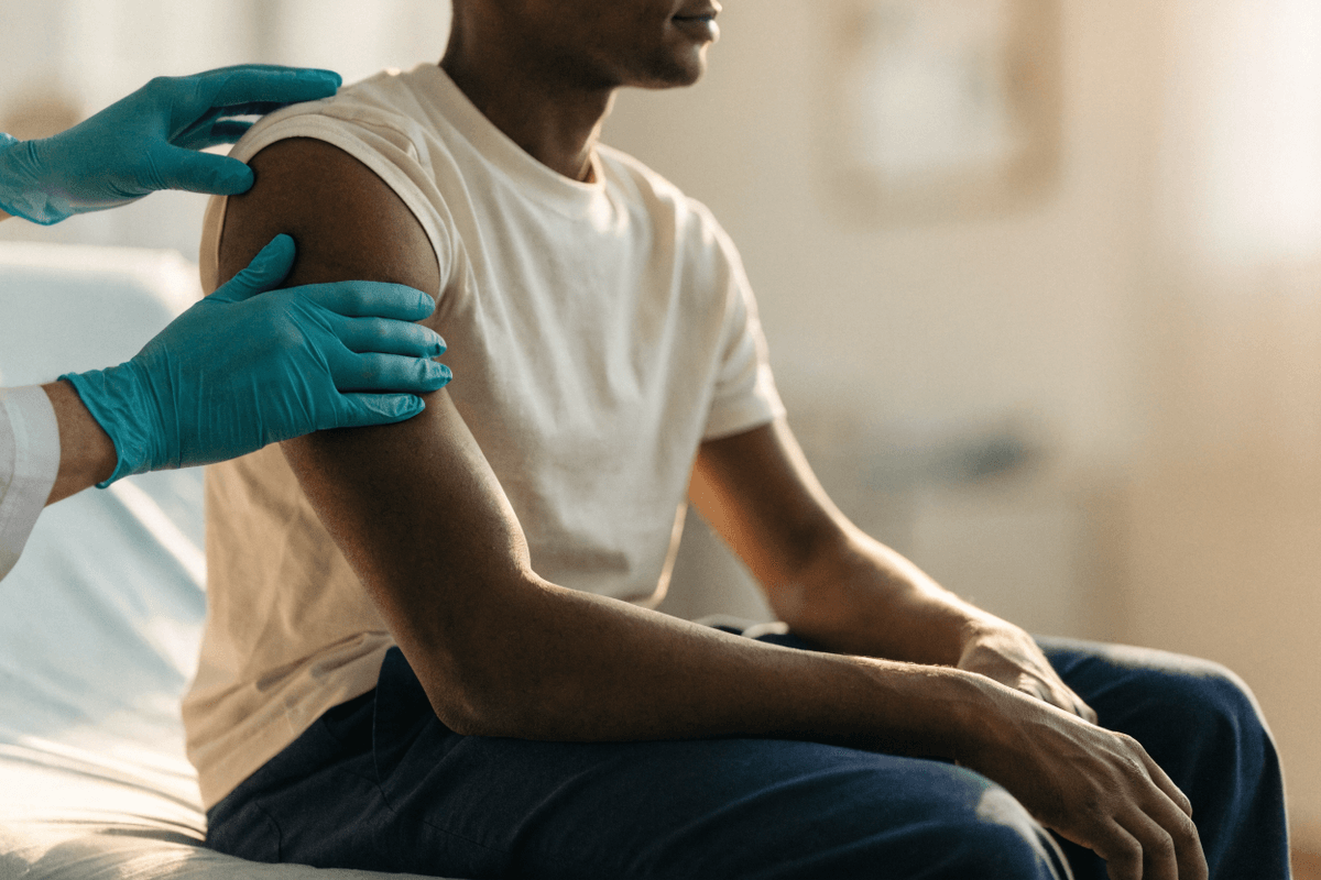 Médico com luvas examina o ombro e o braço de paciente em avaliação de nódulo subcutâneo na C+Med Sapeaçu